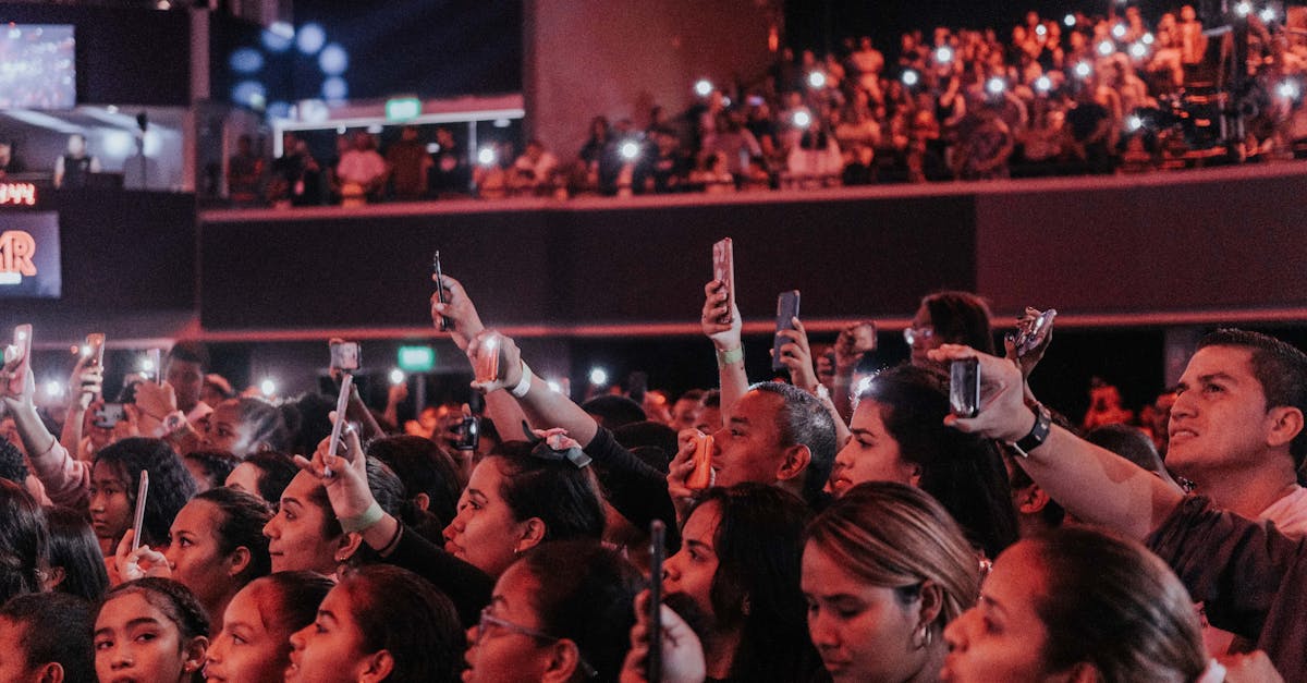 Lively audience enjoying a concert, capturing moments with smartphones in a vibrant atmosphere.