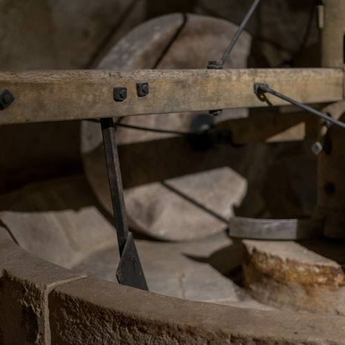 在低光下,一台古朴且古老的磨盘研磨机的特写镜头,展示了其木质和金属组件及风化的质感。