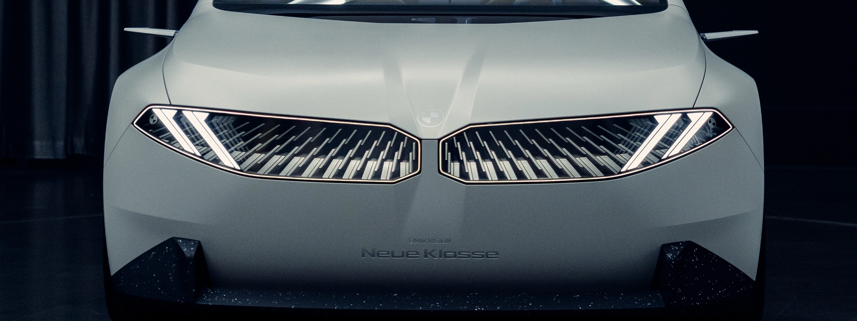 Front view of a car highlighting the grille and headlights in a modern blue-toned setting