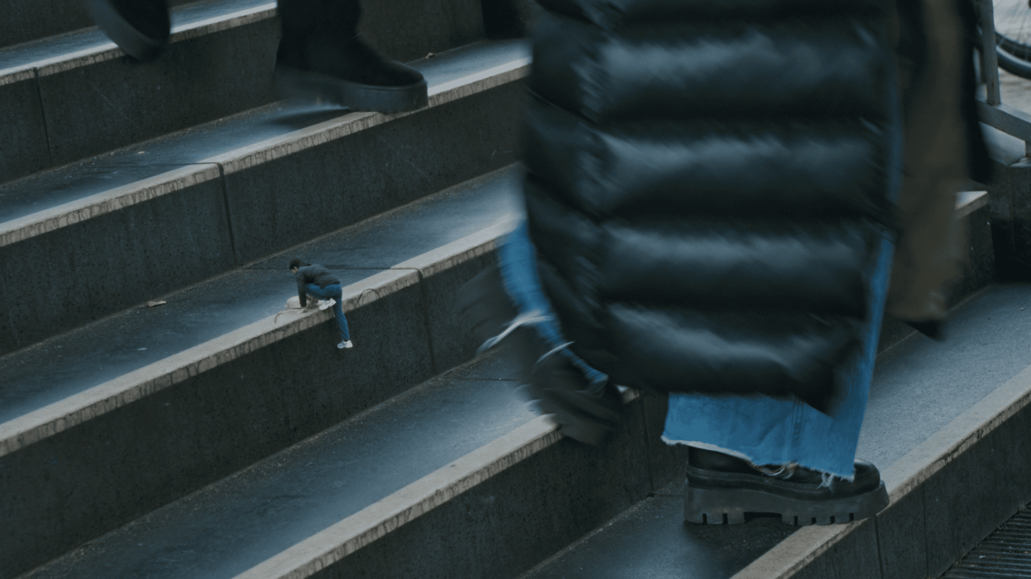 The miniature protagonist climbs U‑Bahn stairs step by step, symbolising perseverance, integration, and slow, hard-won progress.