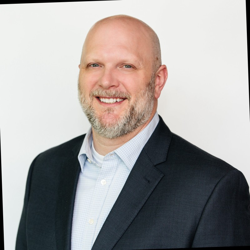Editorial portrait of a young man with wavy hair in a knit sweater, looking over his shoulder in soft light.