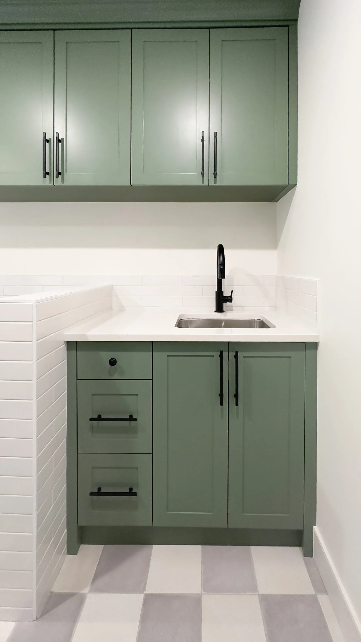 Image of laundry sink with green millwork and light countertops.