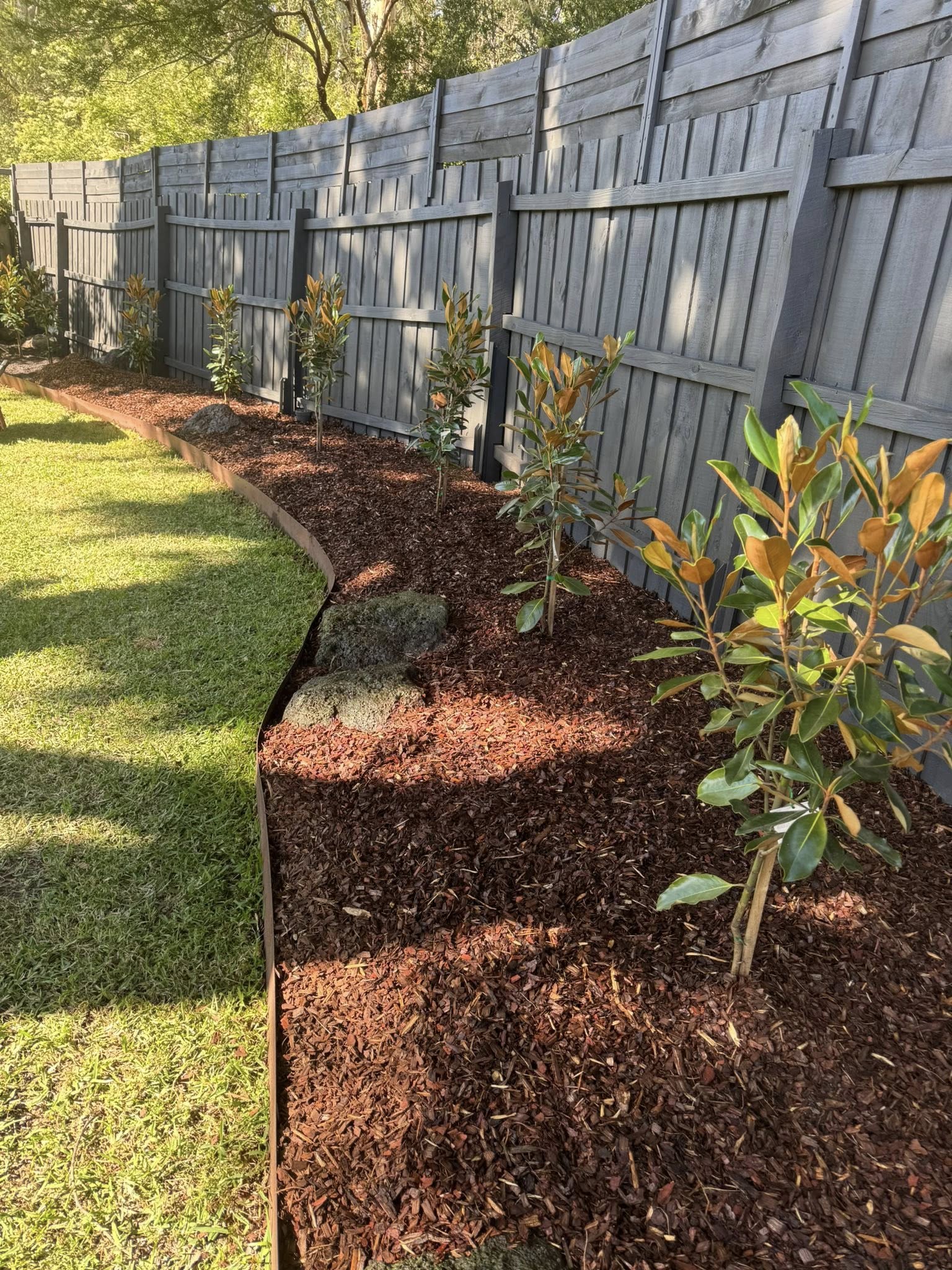 A garden bed cleared, replanted and re-edged along a fence line after a BCW clean-up