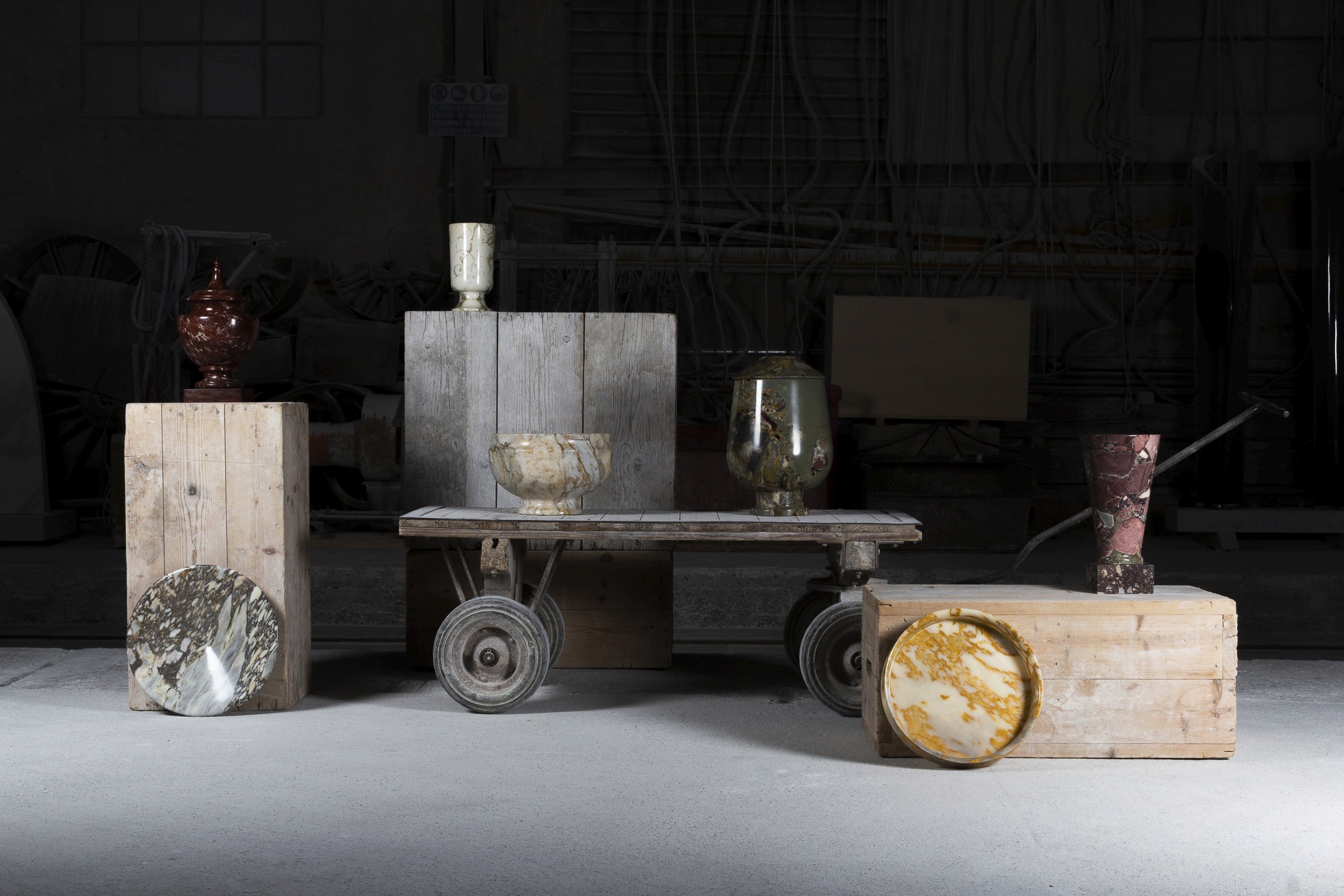 Photo d'objets en marbre mise en scène sur des caisses en bois et dans une brouette