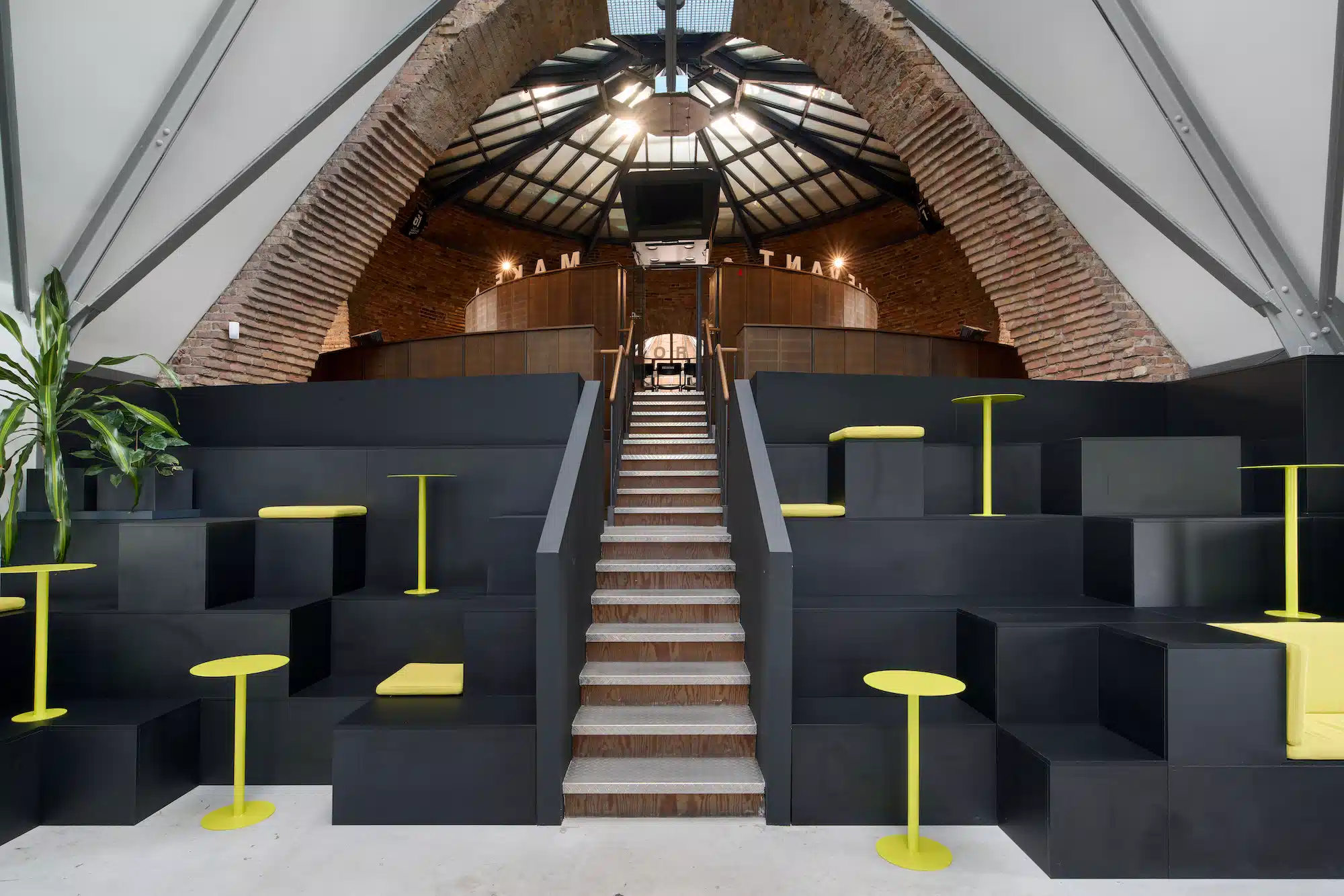 Dojo Office – modular black seating landscape with yellow bar stools under historic brick vault