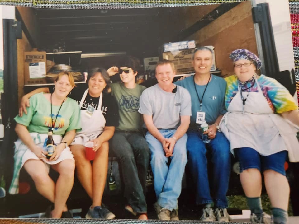 A group of six people posing together in front of a building, smiling and enjoying their time.