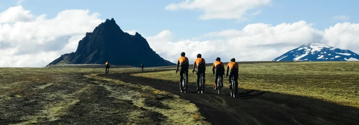 Gravel bike riders pedal towards a mountain on an Icebike tour