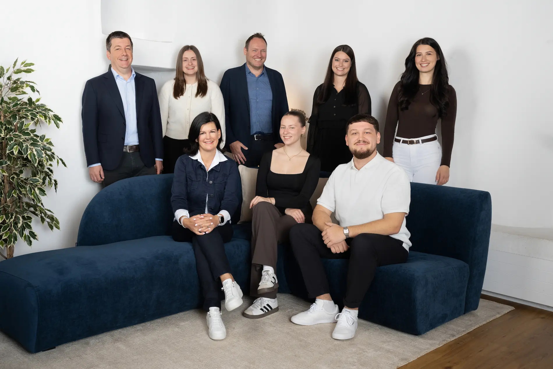 Team von Kocher Immobilien sitzt auf Treppe vor Gebäude und posiert gemeinsam