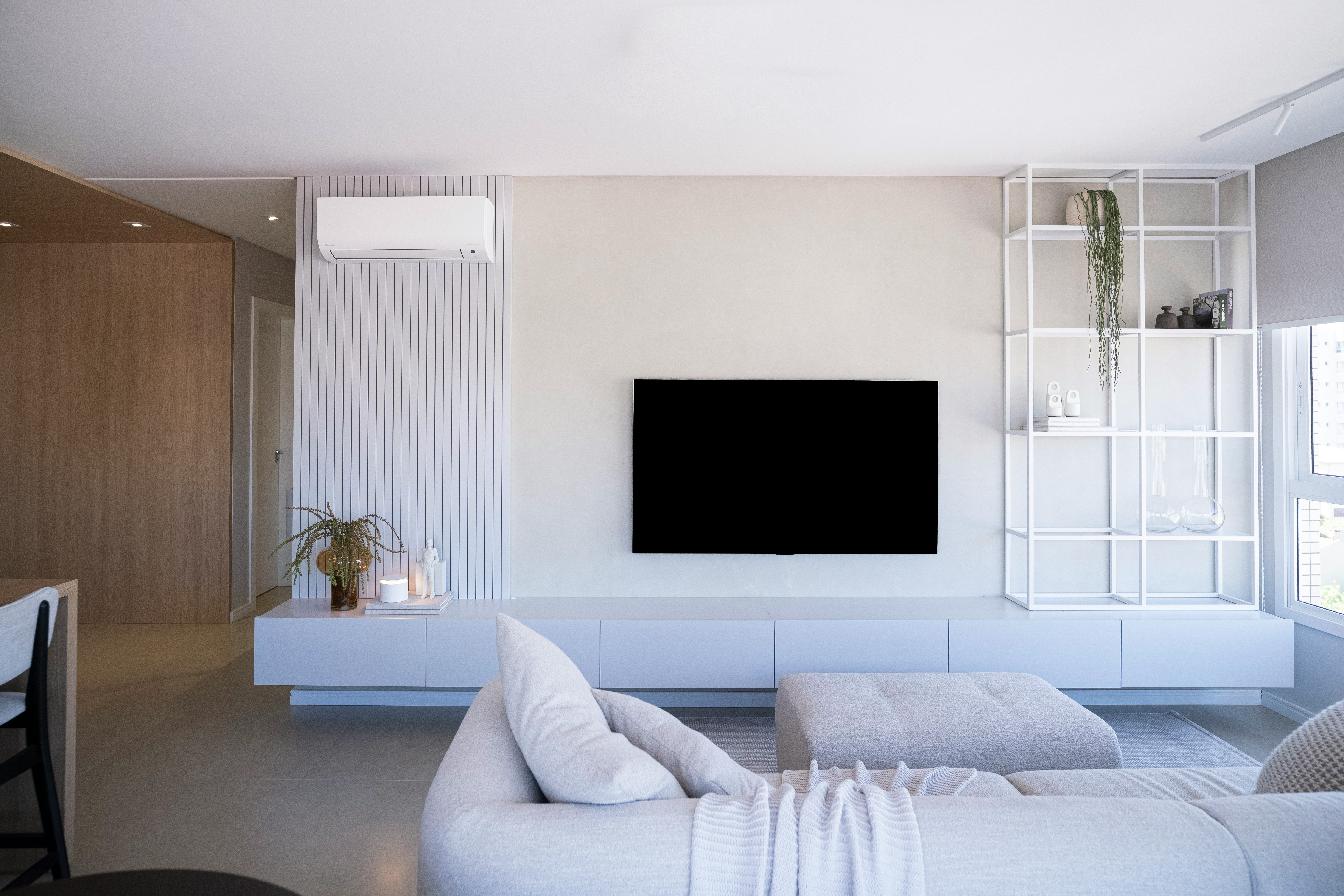 Modern living room with white furniture and large television.