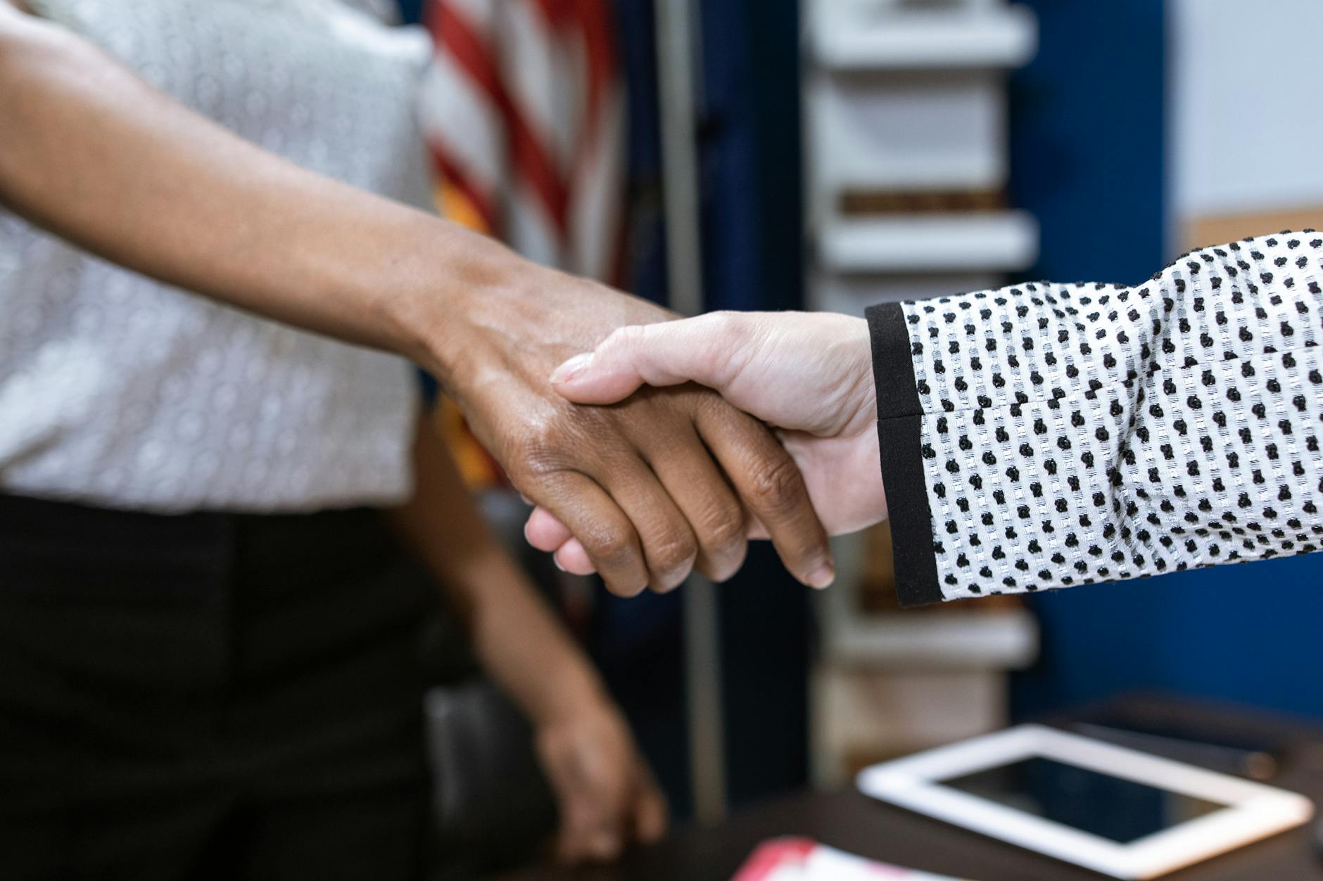 A professional woman shakes hands with a local business owner in front of a storefront to start work based learning.