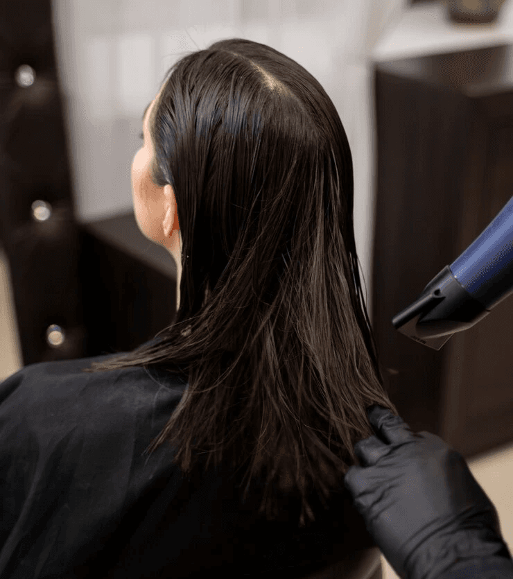 Chica con cabello oscuro de longitud media siendo secado por un estilista, durante el servicio de coloración completa en Peluquería Carlos y Hugo Spa en Arequipa