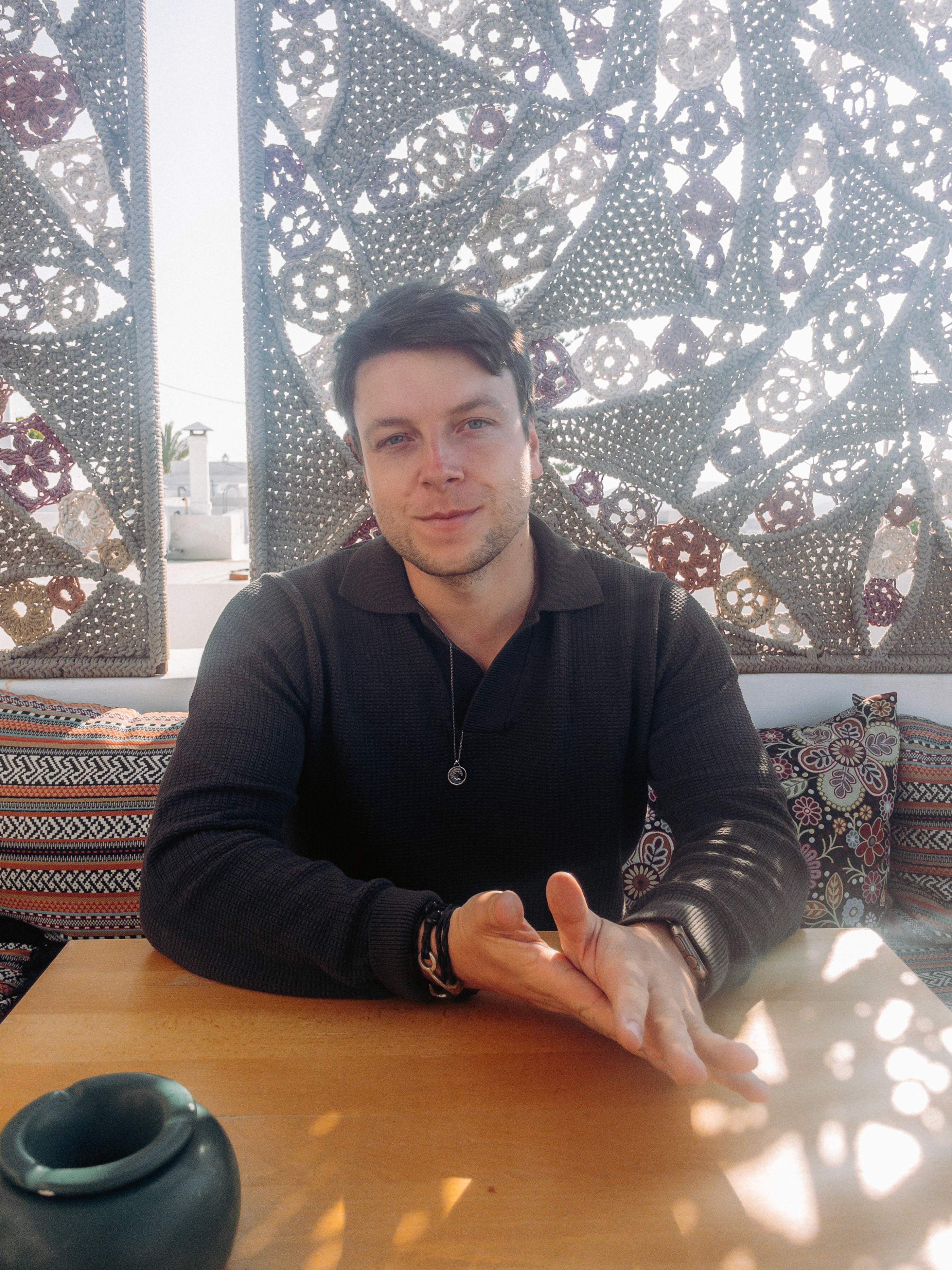 Group of people gathered around a wooden table with laptops, shaking hands during a team meeting.