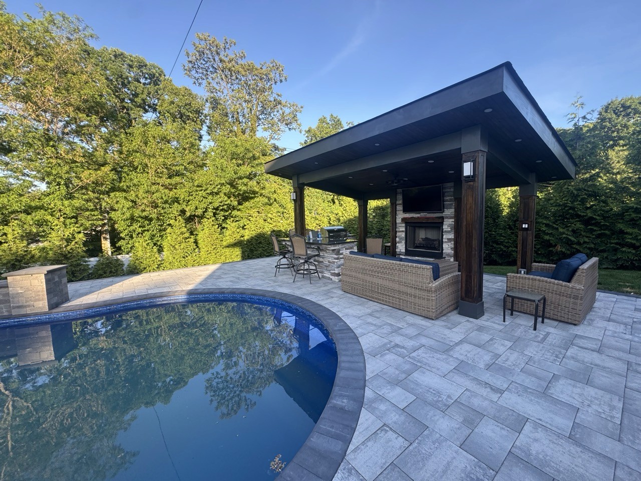 In-ground pool with a covered pavilion and paver deck by CMC Masonry
