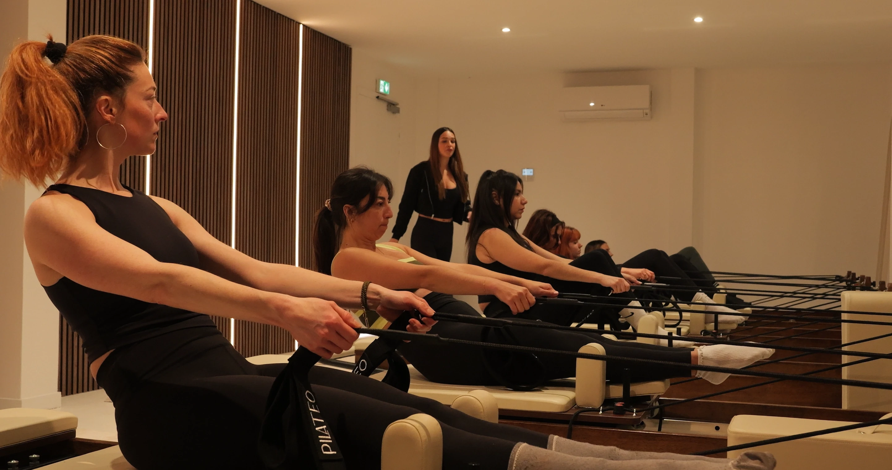 Cours de Pilates avec coach, groupe de femmes en salle de sport.
