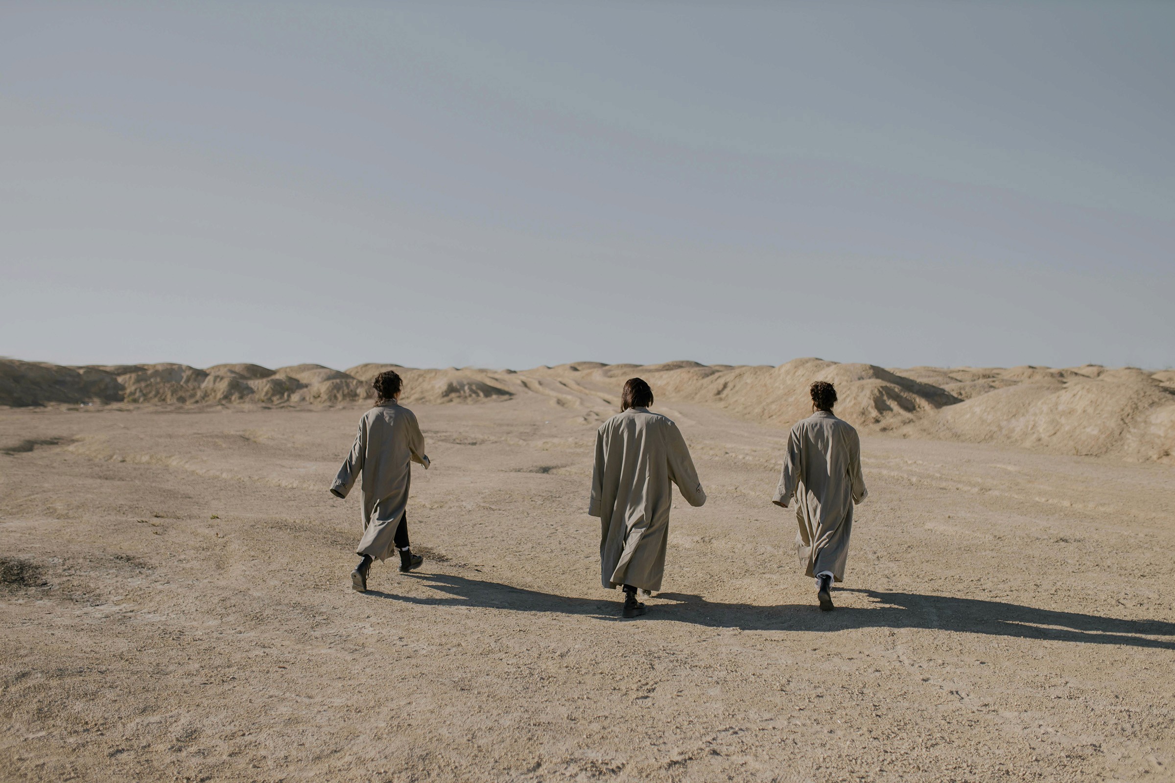 Three people walking through the desert