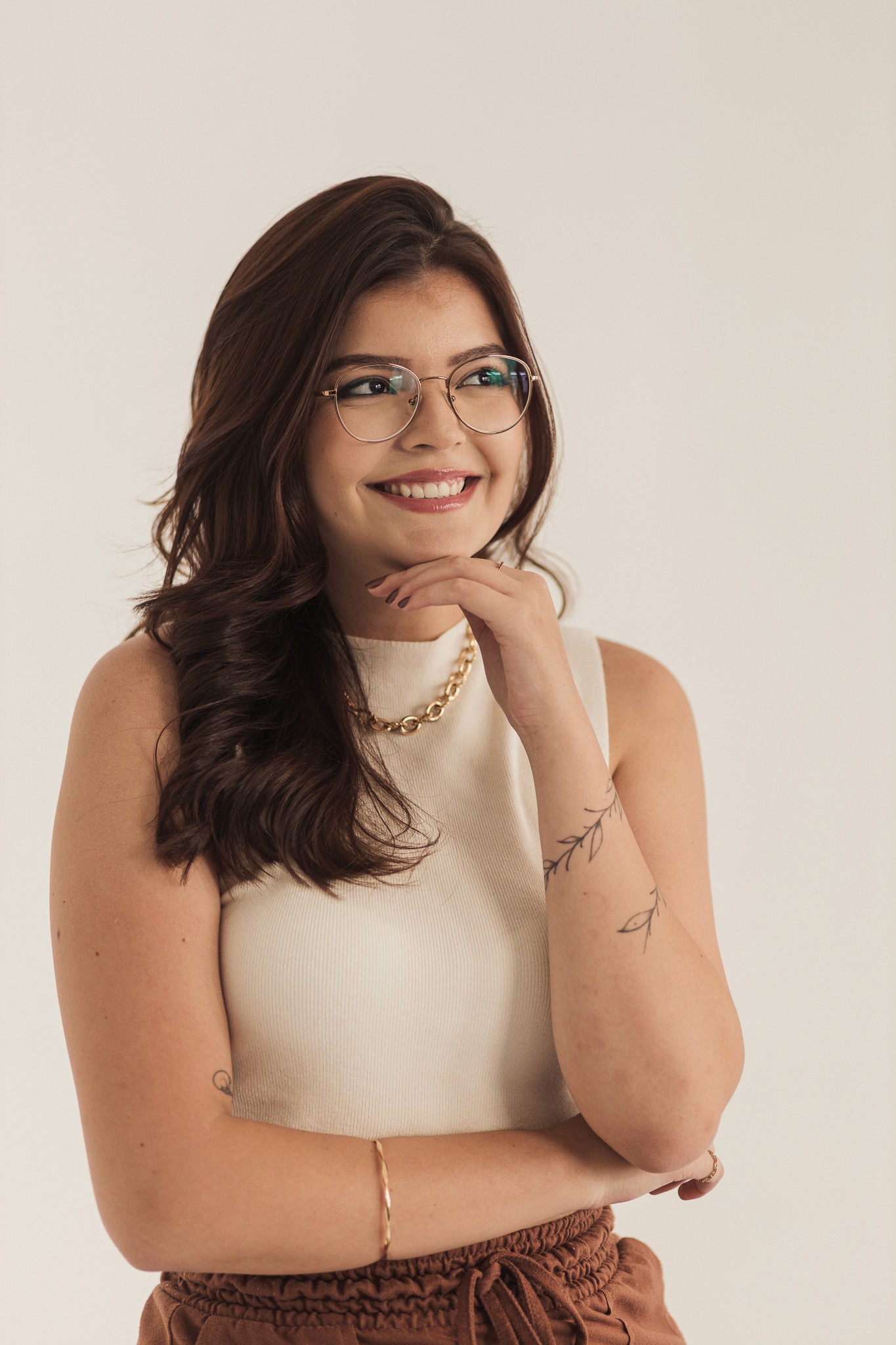 Homem sorridente com camisa polo cinza em frente a uma parede azul com papéis ao fundo