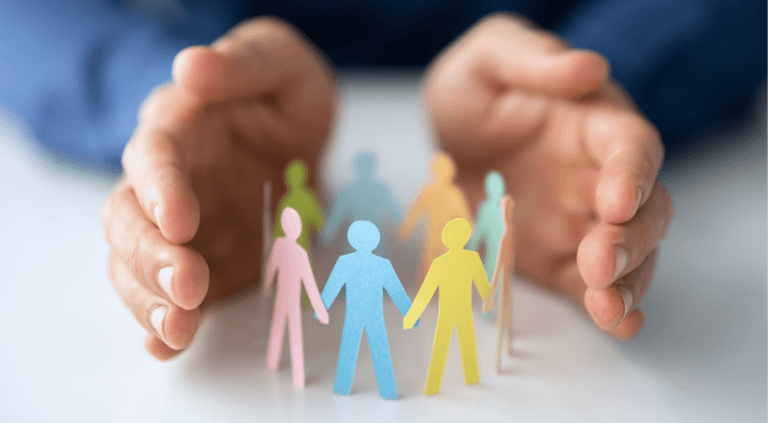 Two hands cupped together protecting small paper cutout figures of people, symbolising safeguarding and care