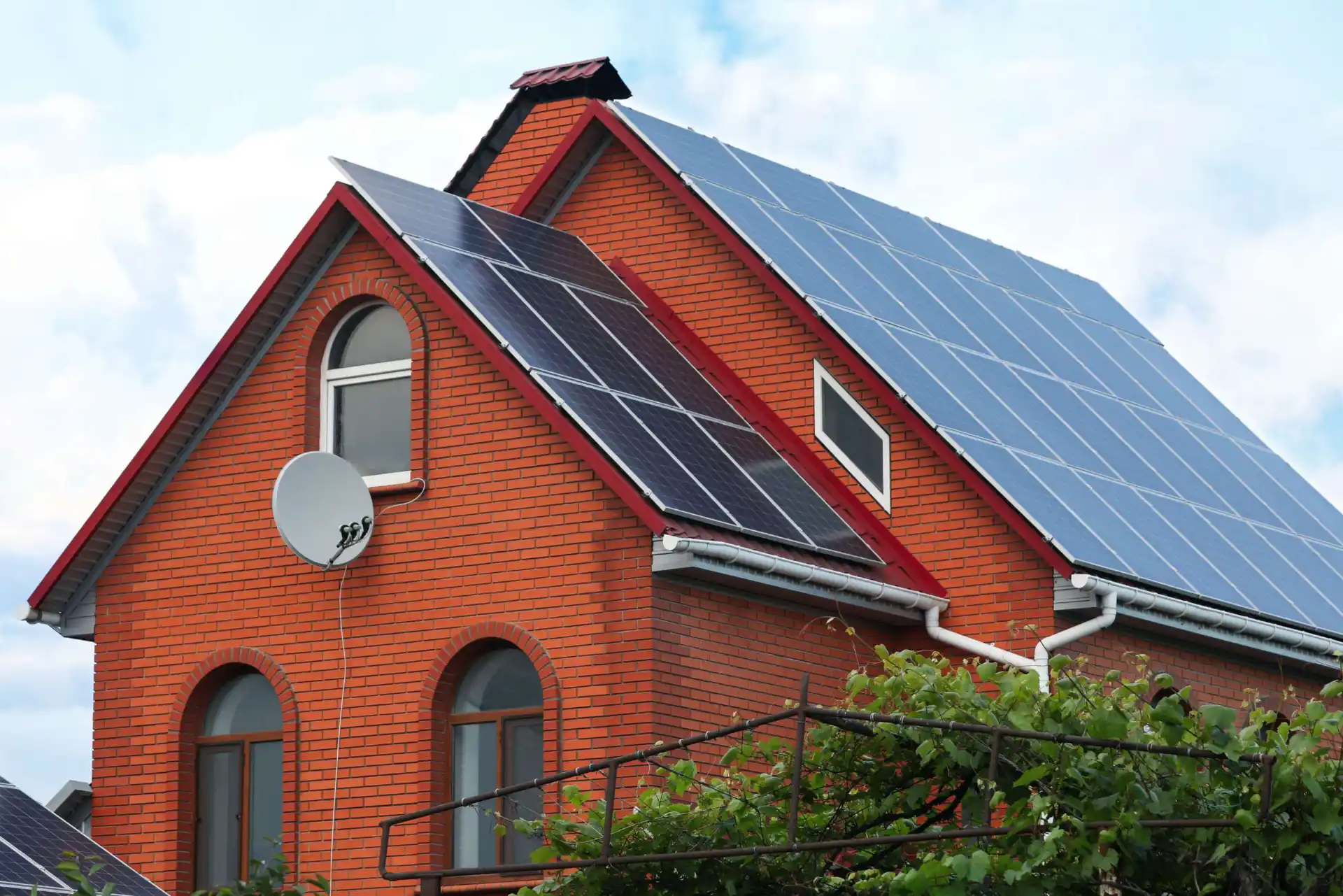Ziegelhaus mit Solarpanels auf dem Dach und Satellitenschüssel, umweltfreundliche Energiequelle.