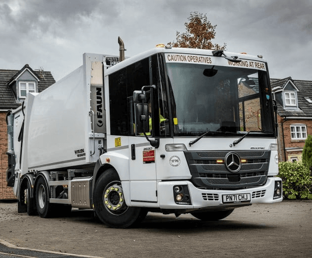 Close-up of a dark green leaf showing its textured surface and central vein against a muted background.