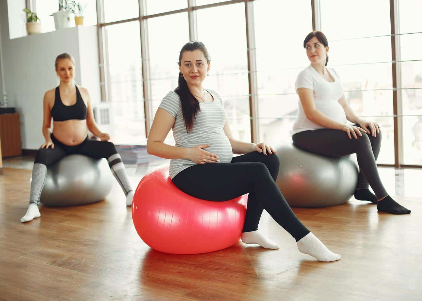 Pilates while pregnant - Three women sitting on exercise balls at a prenatal Pilates class