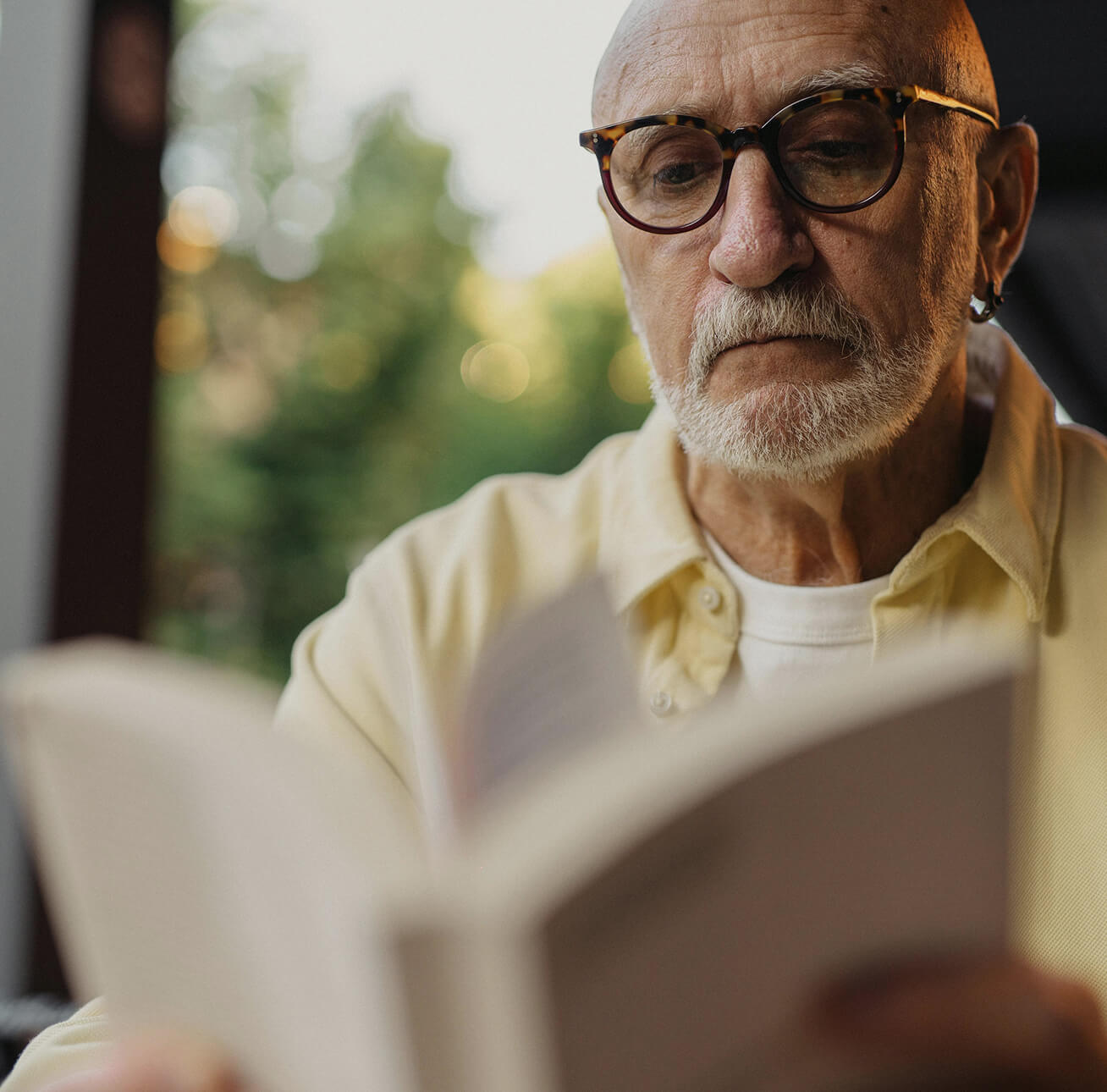 An older man with glasses reading a book