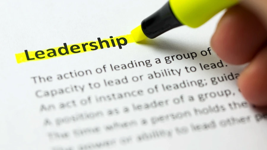 Close-up of a hand using a yellow highlighter to emphasize the word “Leadership” on a printed page, symbolizing focus on leadership and guidance concepts.