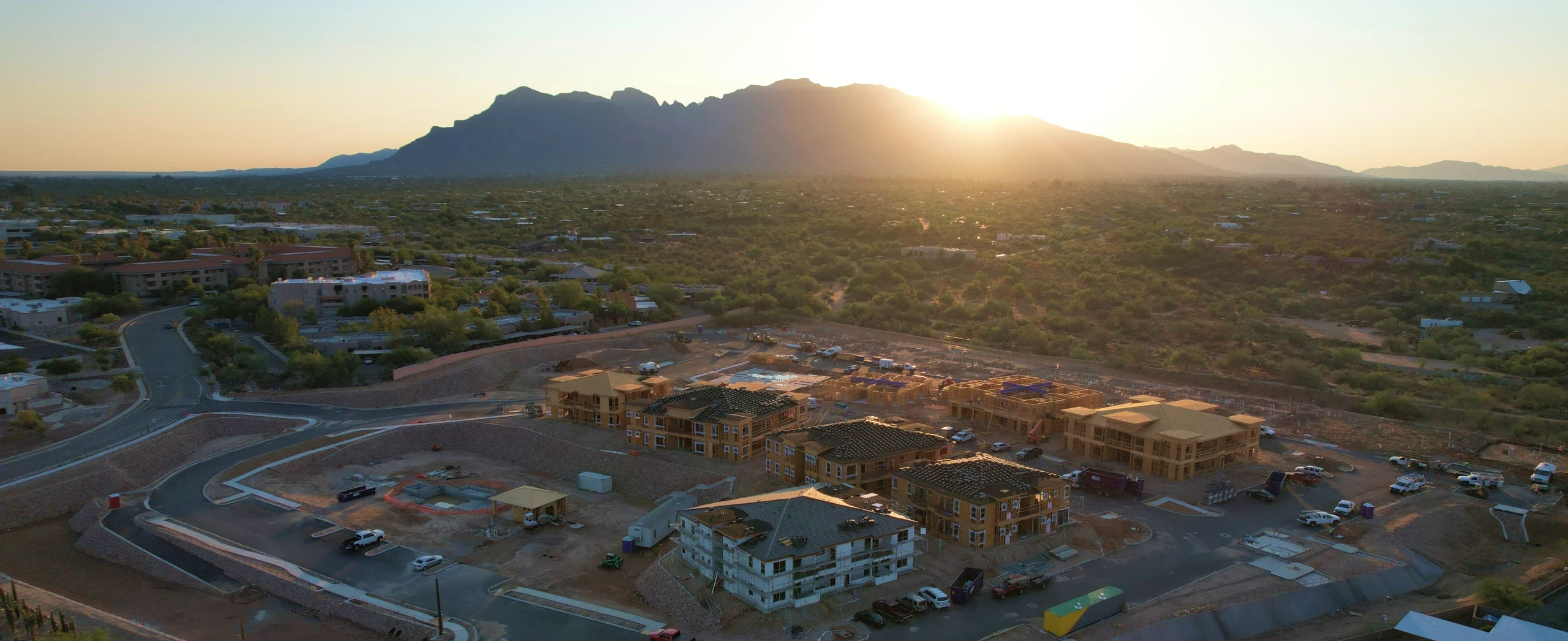 Aerial view of a construction site surrounded by mountains, showcasing ongoing development against a natural backdrop.