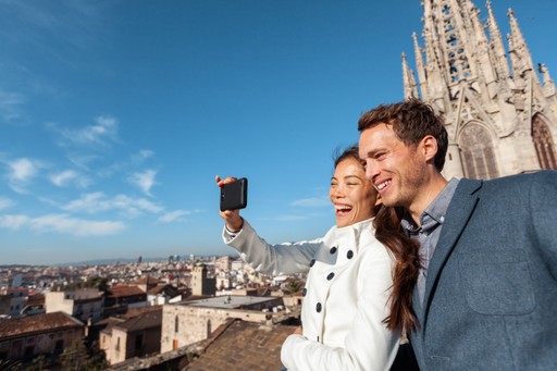 Couple taking a selfie with a city skyline and cathedral in the background.
