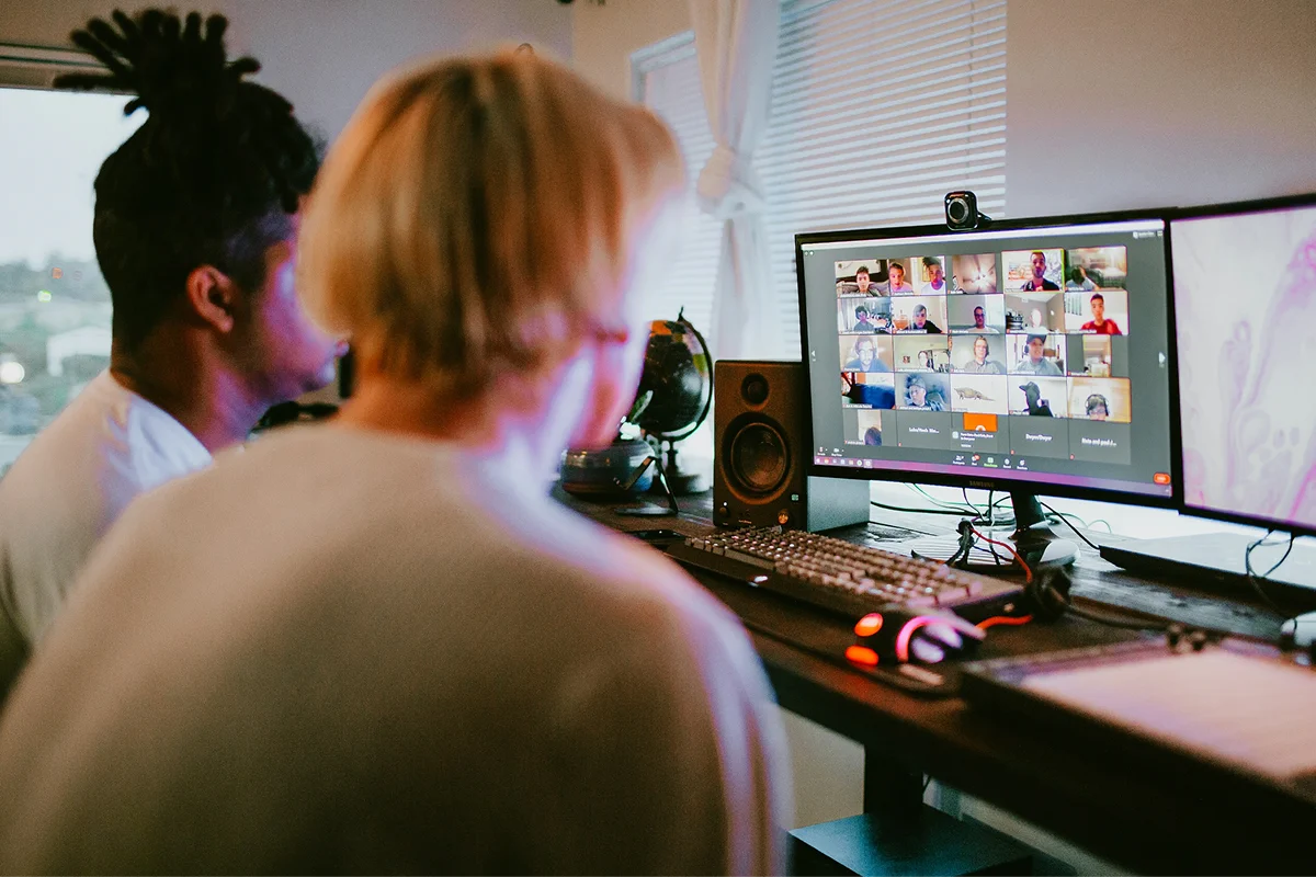 Two people watching a group video call on a desktop computer.