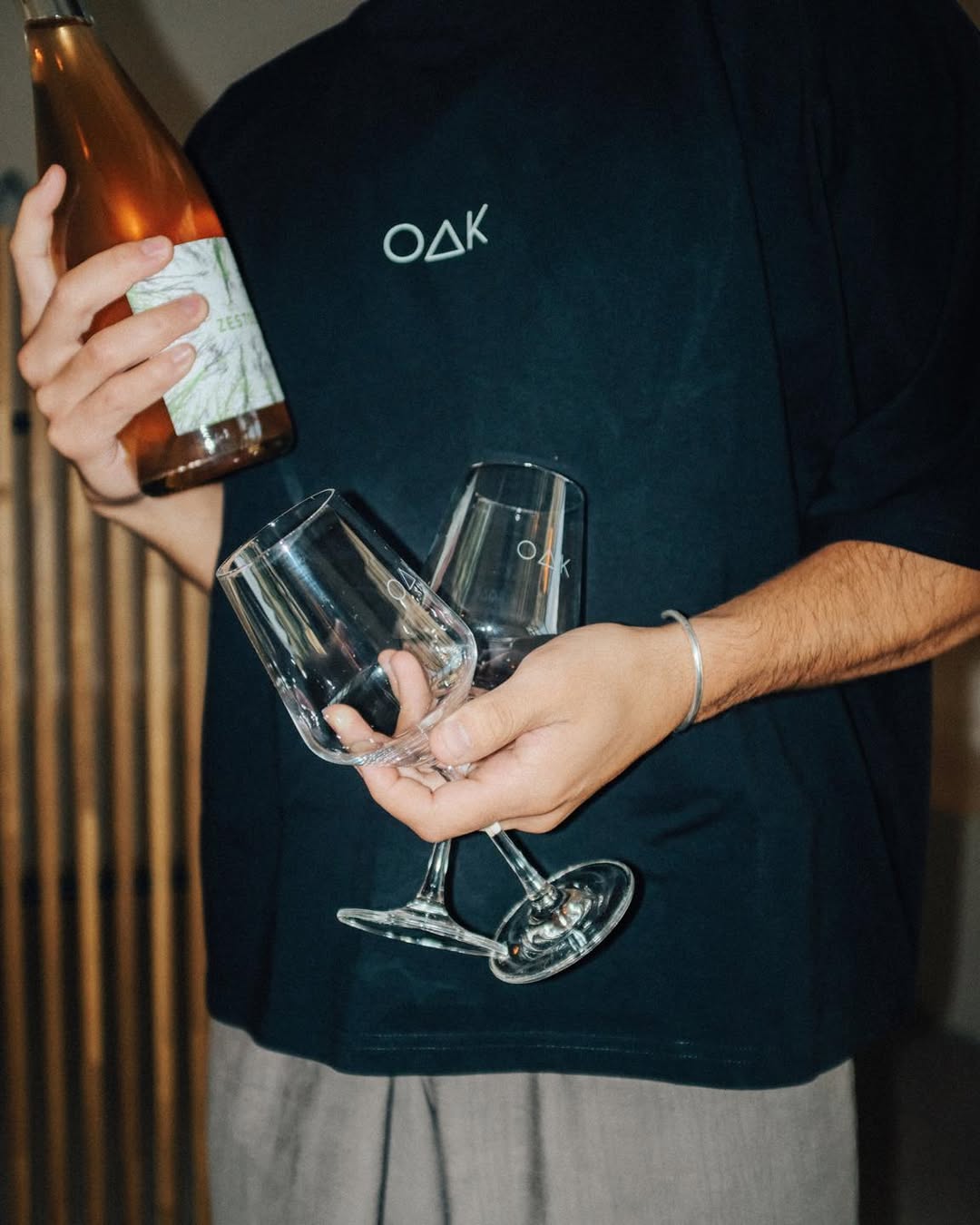 Oak & Saint staff member holding wine glasses and bottle inside the café and wine bar.