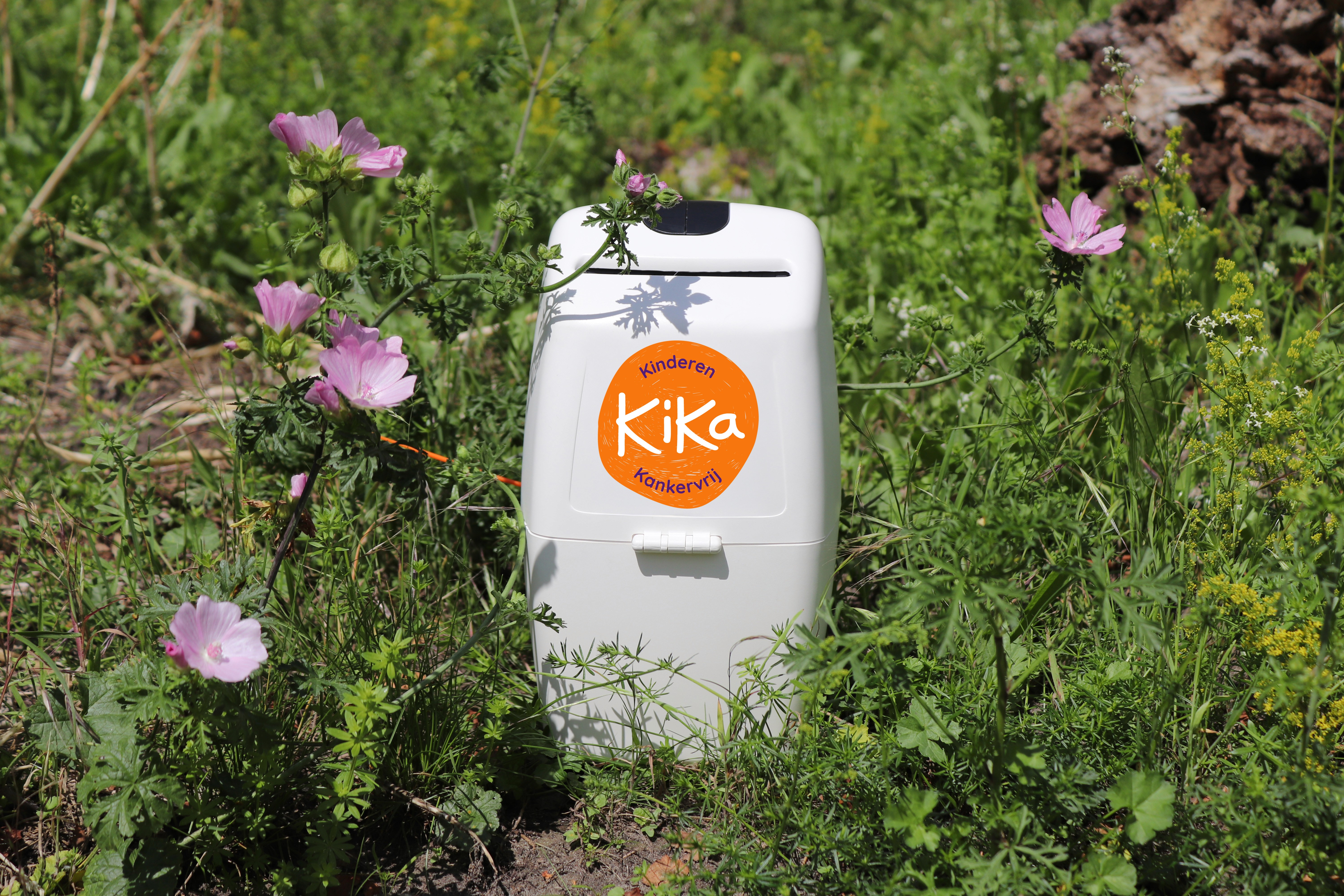 Collectebus van KiKa die tussen gras en bloemetjes staat