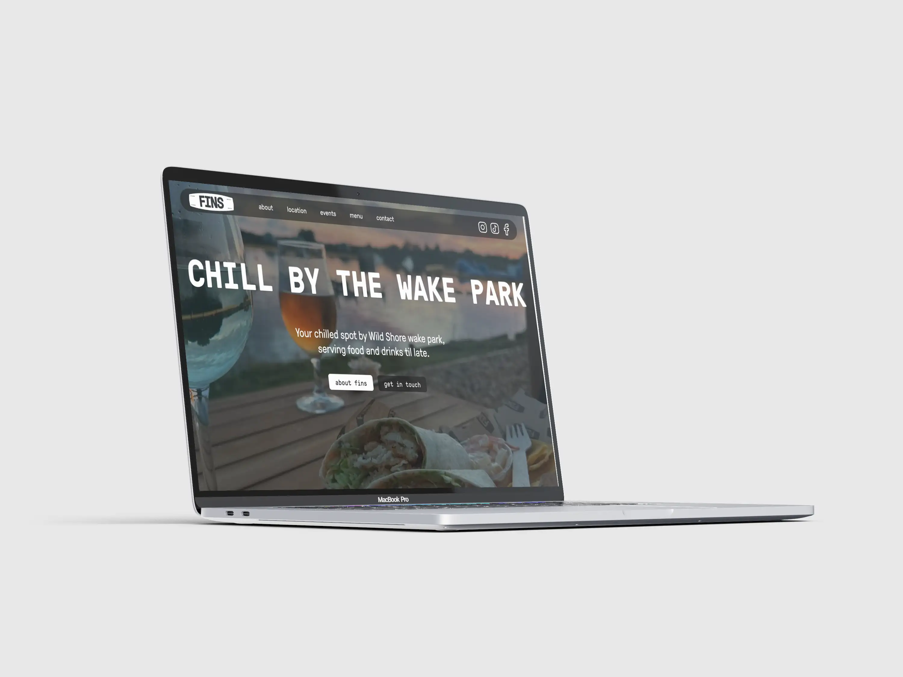 FINS Café Bar website displayed on a laptop, showing its wake-park setting, food and drinks photography and branded page design.