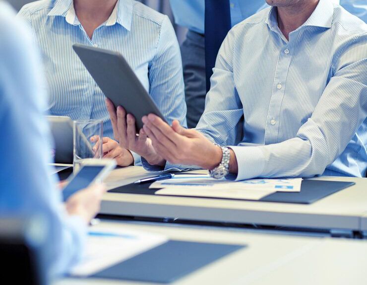 A talent recruiter with a soft smile working on her laptop in the office. The angle is on her face so we can't see what's is on the screen. She is wearing a blazer