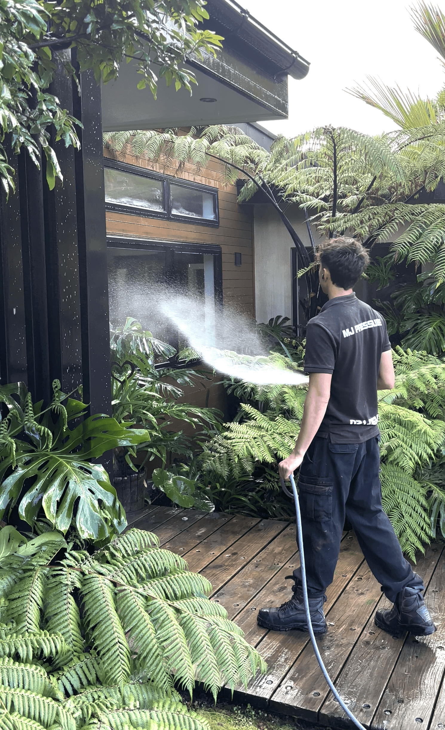 Josiah soft washing a Hamilton home exterior with professional cleaning equipment
