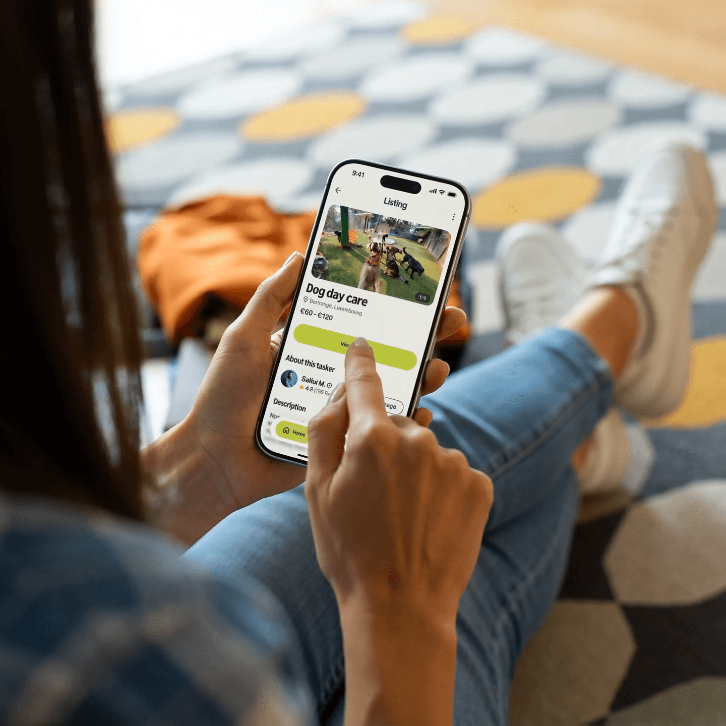 A woman sitting on the floor using her phone to book a dog day care service