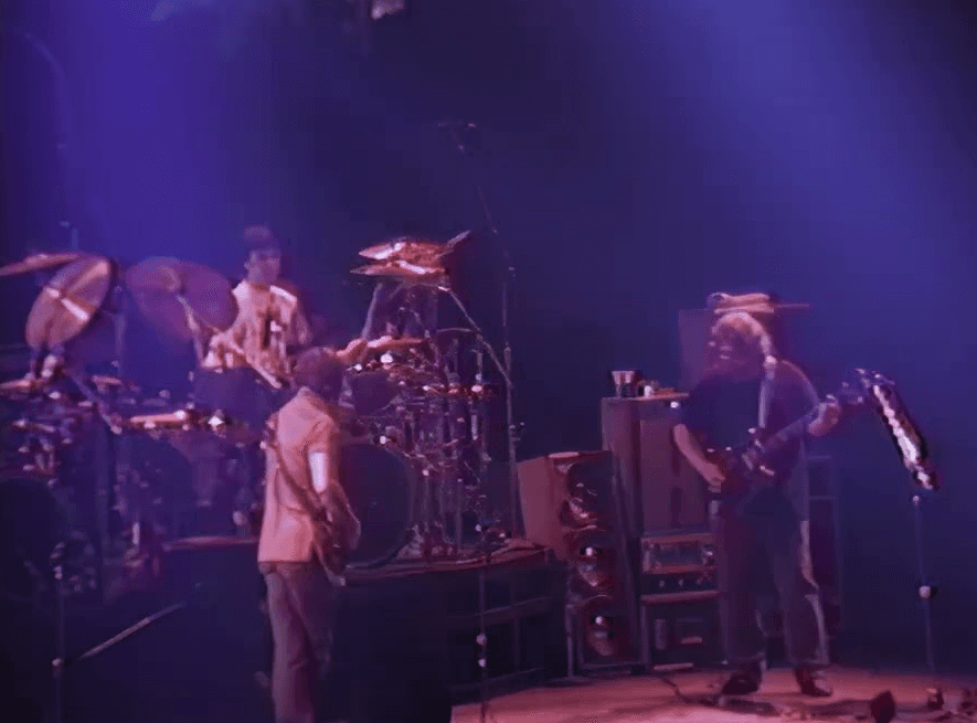 A live band performing on stage with colorful lights illuminating the scene.