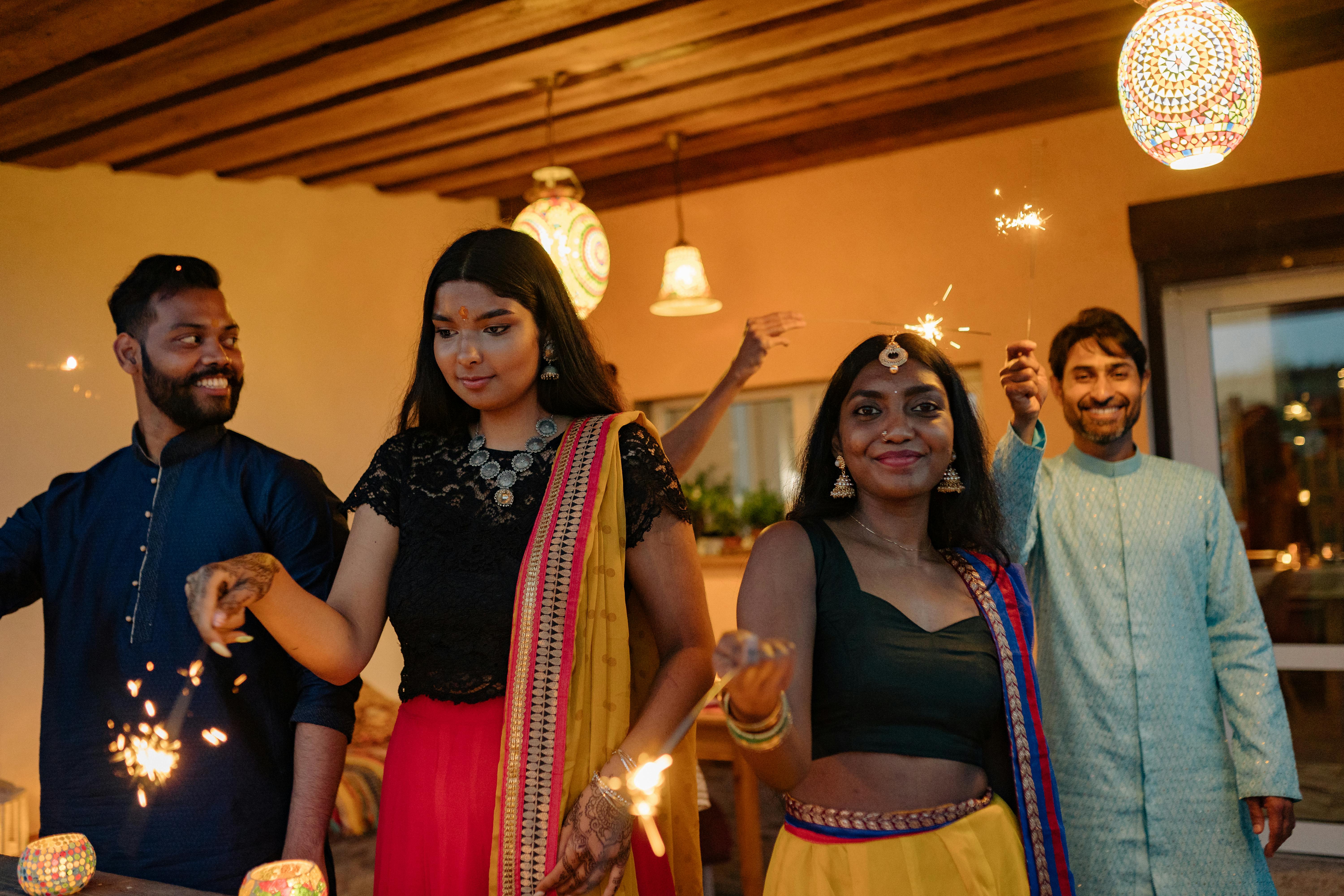 A modern hallway features vibrant teal and orange geometric and leaf patterns, with glossy tiled floors, a large rectangular light fixture, and a small shelf holding a potted plant, all leading to a large, frosted window at the end.