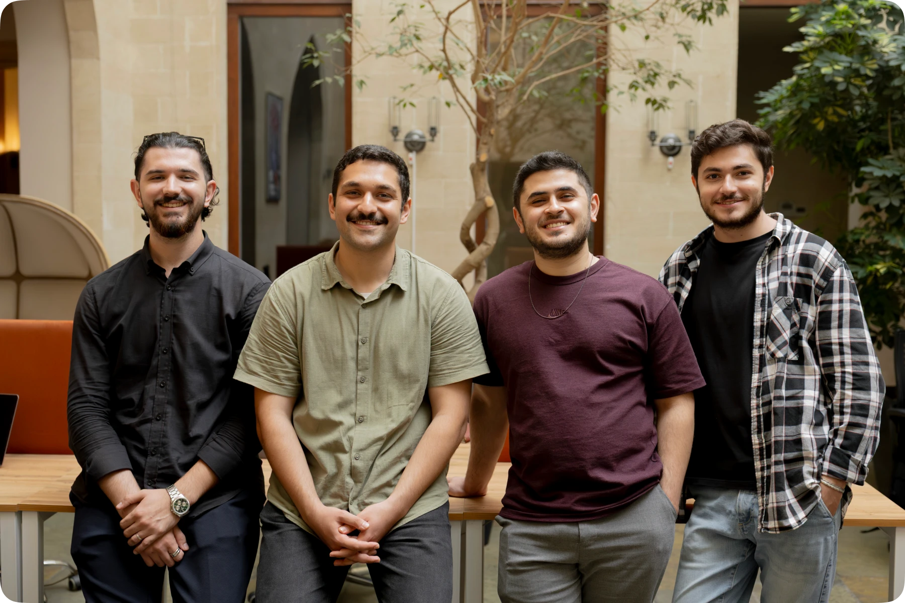 The four founding team members of the Askiva AI startup smiling together in their workspace.