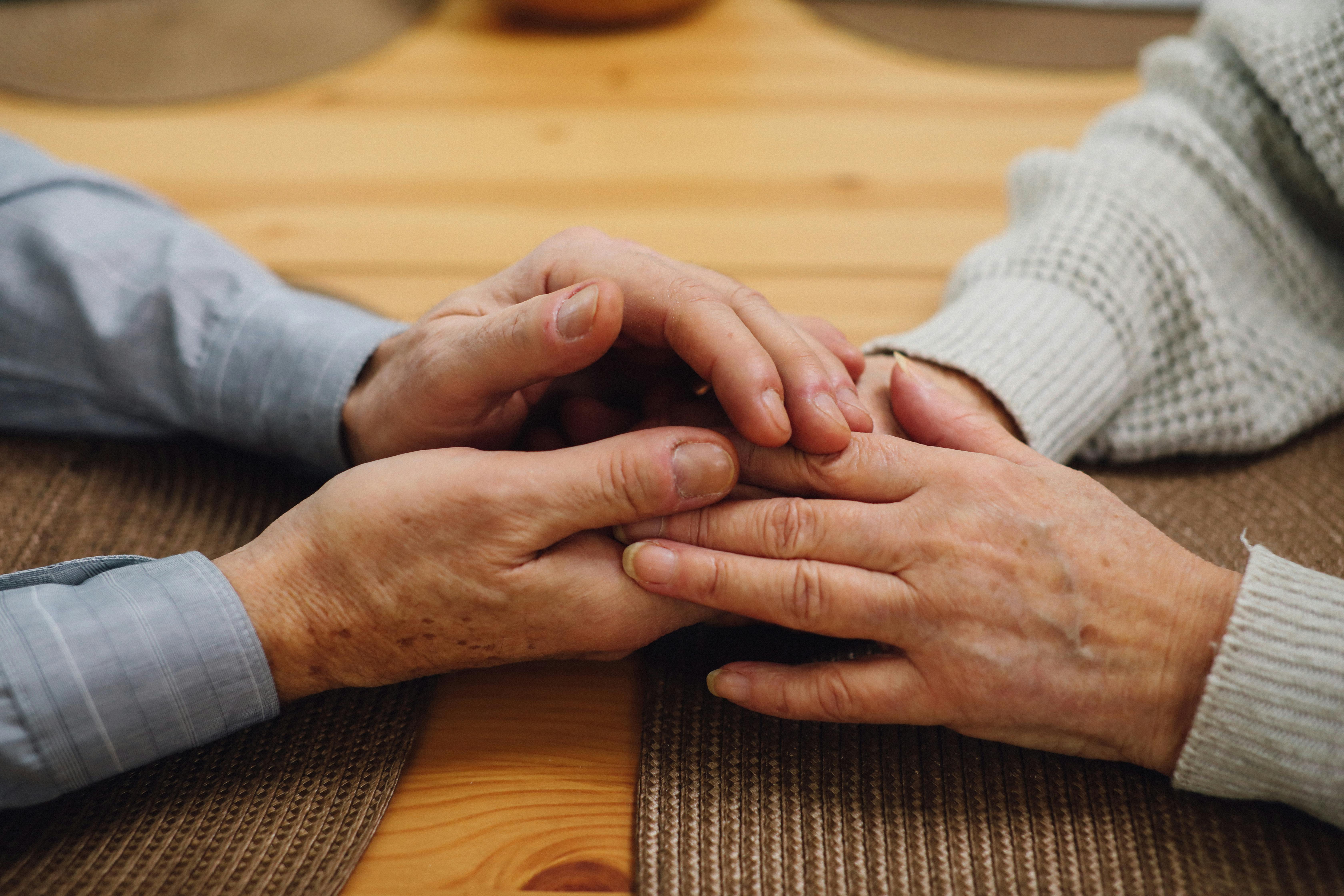 Older couple holding hands at a table — symbolizing emotional connection and intimacy later in life