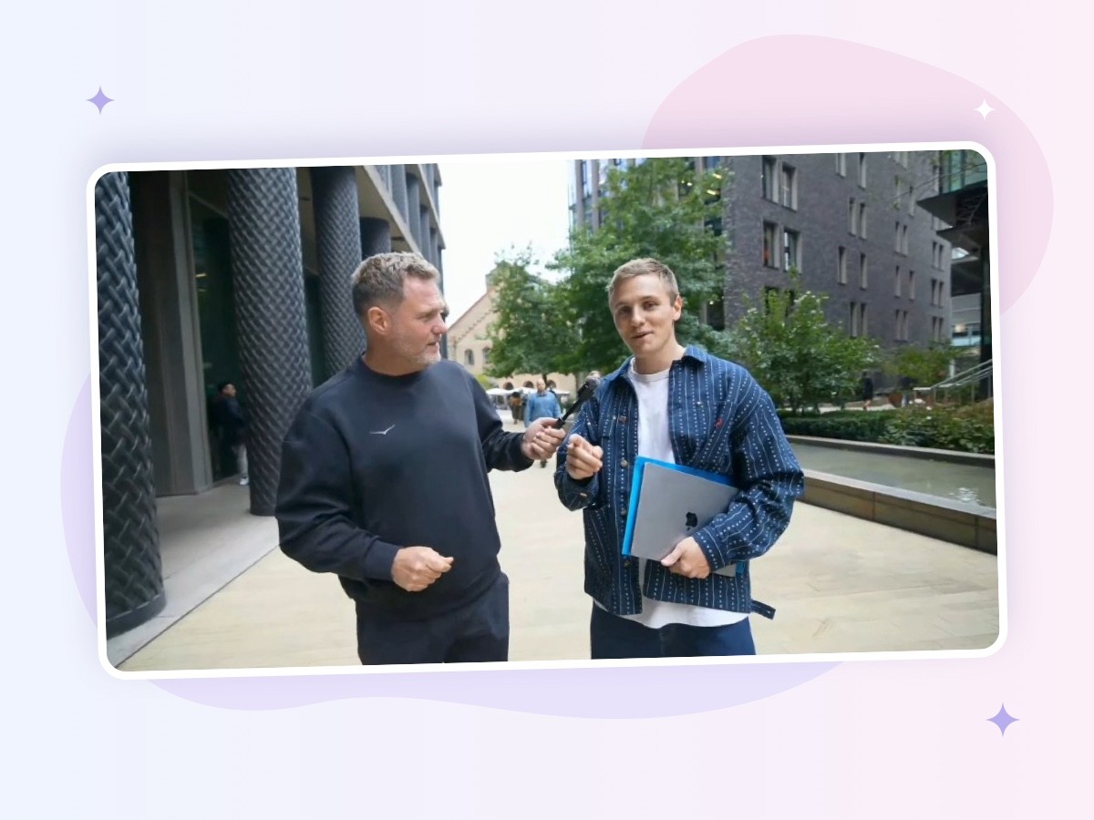 Jamie Wace, holding a laptop, talks to Simon Squibb, who holds out a microphone, on a city street during Simon’s What’s Your Dream? livestream.
