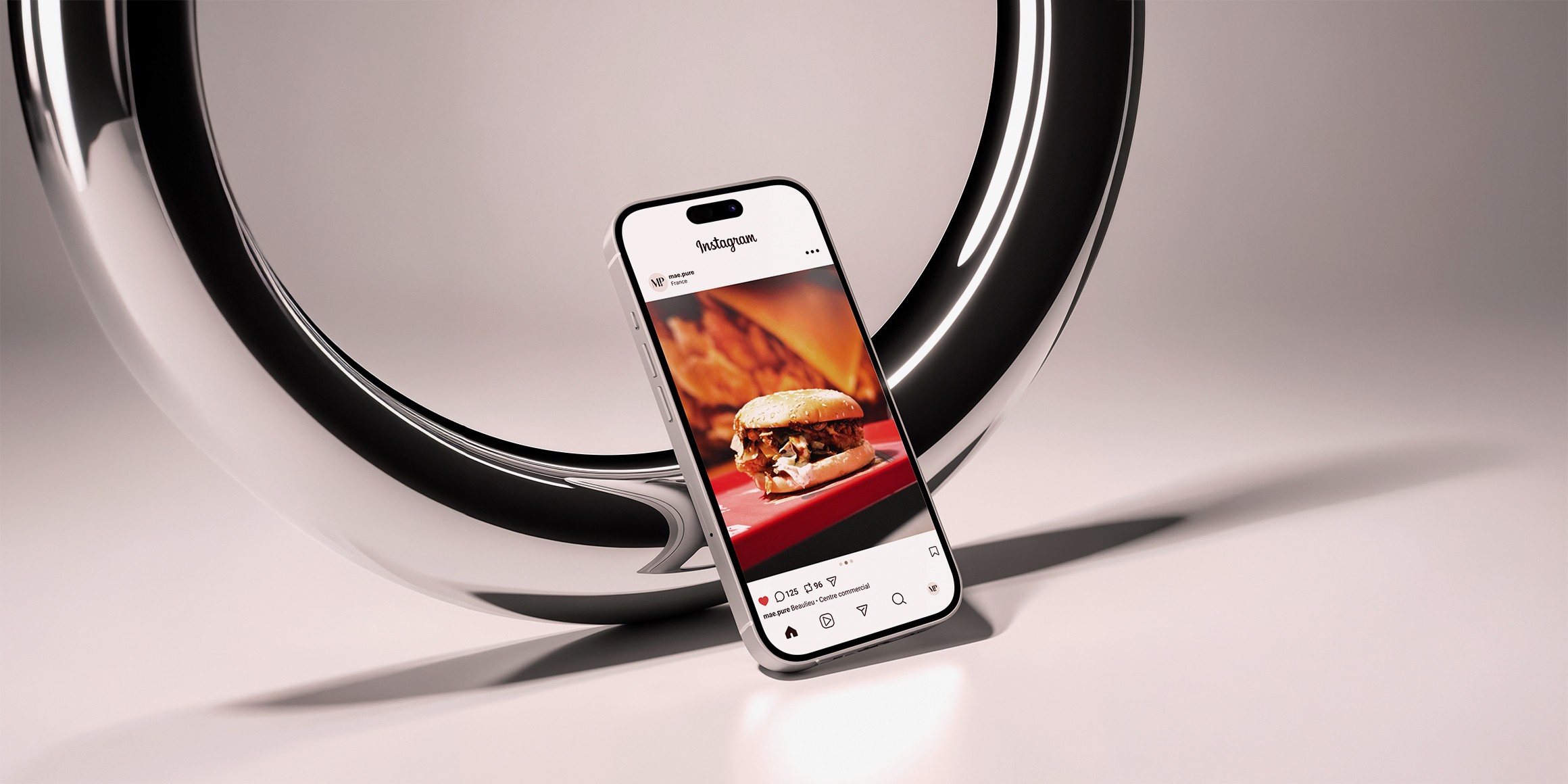 Photo de couverture du projet. Mockup dans un téléphone d'une publication instagram réalisée pour le centre commercial Beaulieu à Nantes. Il s'agit d'un burguer. Le fond est sobre et chromé.