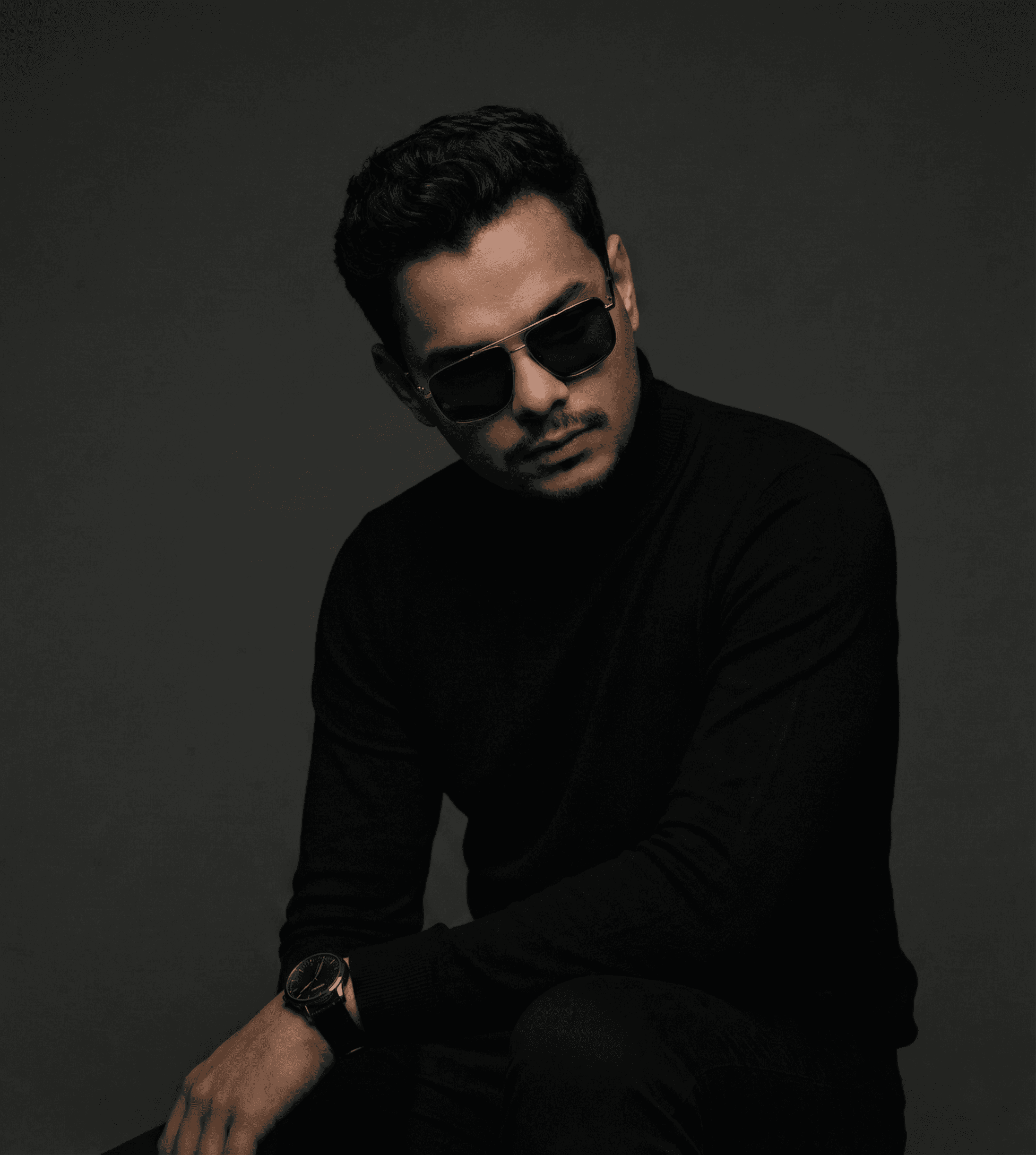 Stylish man with mustache in black turtleneck and aviator sunglasses.