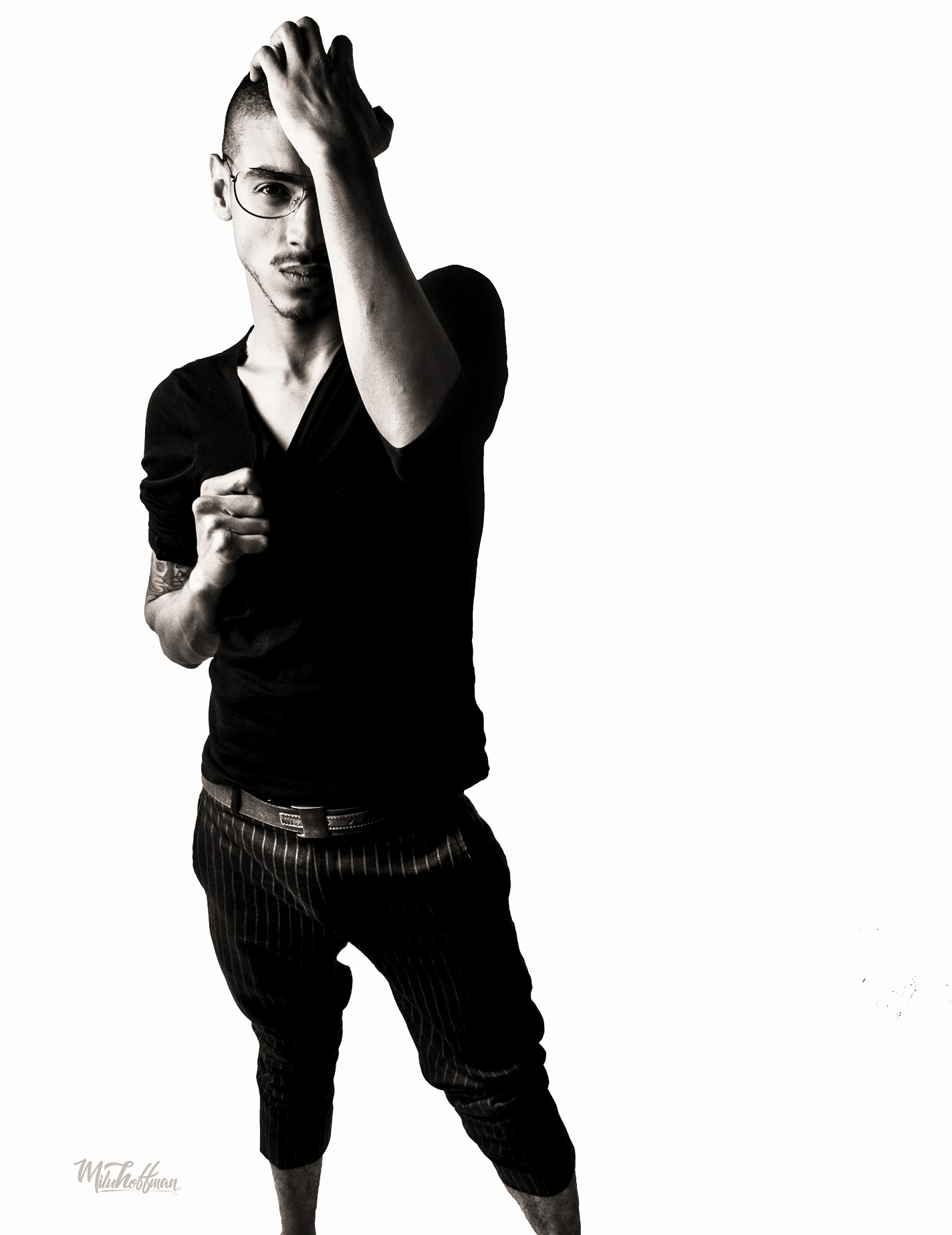 Artistic studio photography exploring light and shadow, featuring a male subject with hands positioned to create leading lines and a minimalist, editorial composition.