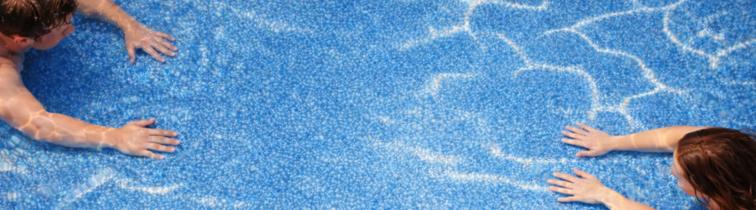 Couple swimming towards eachother in luxury backyard pool