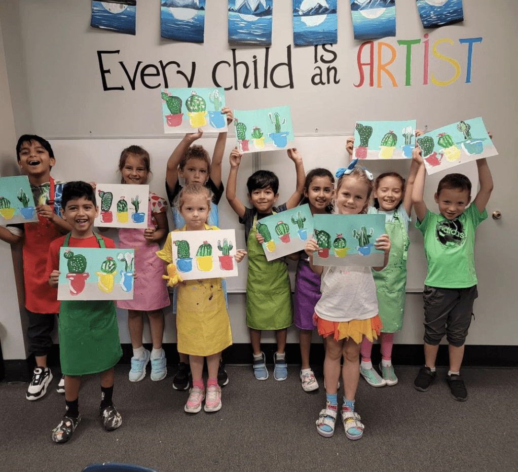 An art class posing with their work in the art studio at SportPlus Charlotte