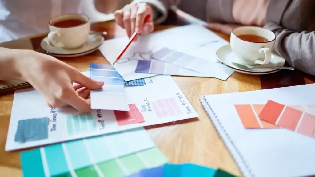 a person holding a pencil and looking at a color swatch