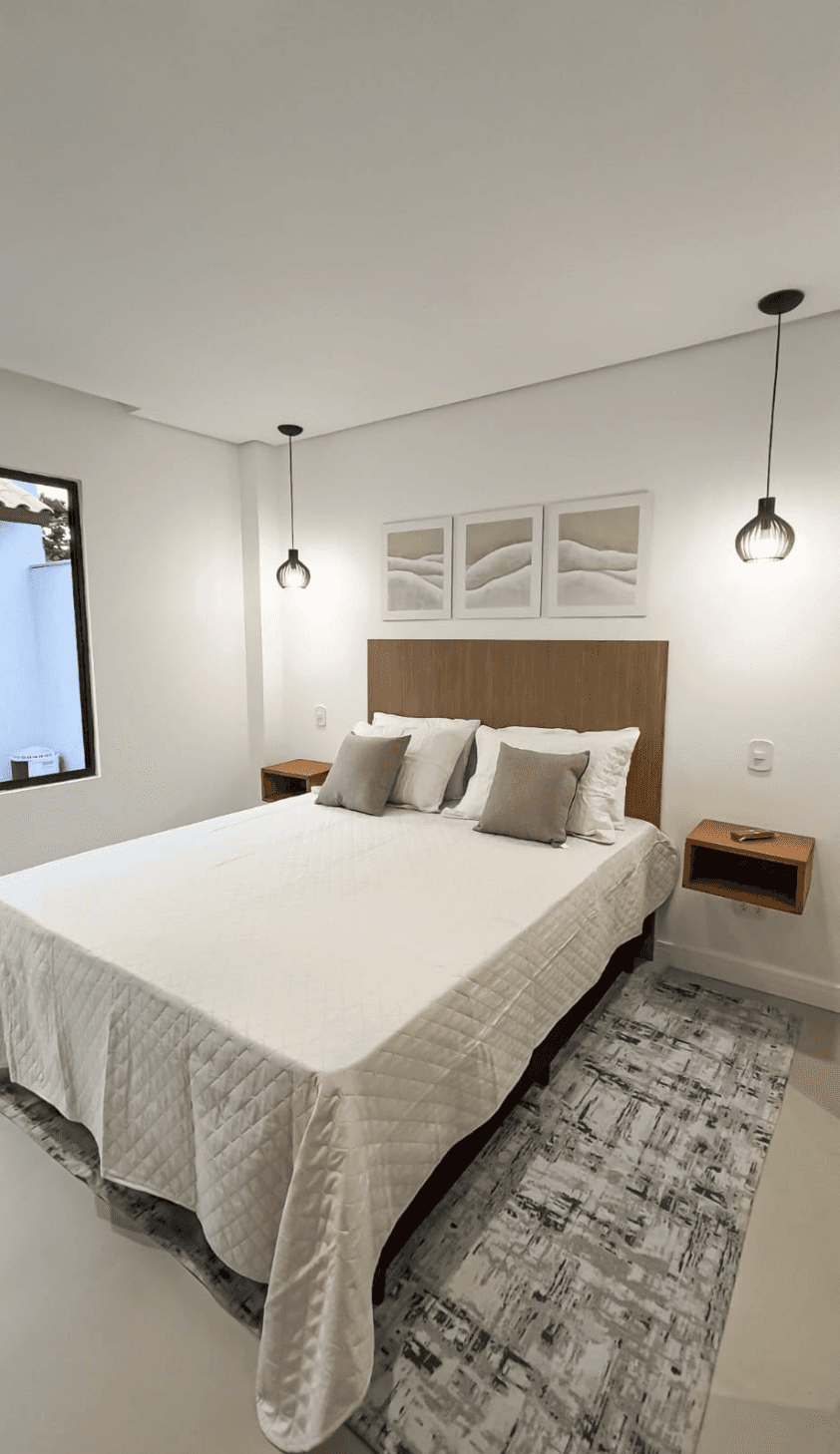 crisp white bedding, layered pillows, a plush bench at the foot of the bed