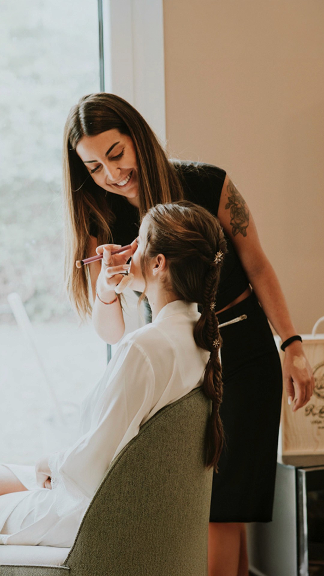 A luxurious bathtub filled with water and floating rose petals, surrounded by candles and greenery. The soft lighting creates a tranquil and romantic spa-like atmosphere.