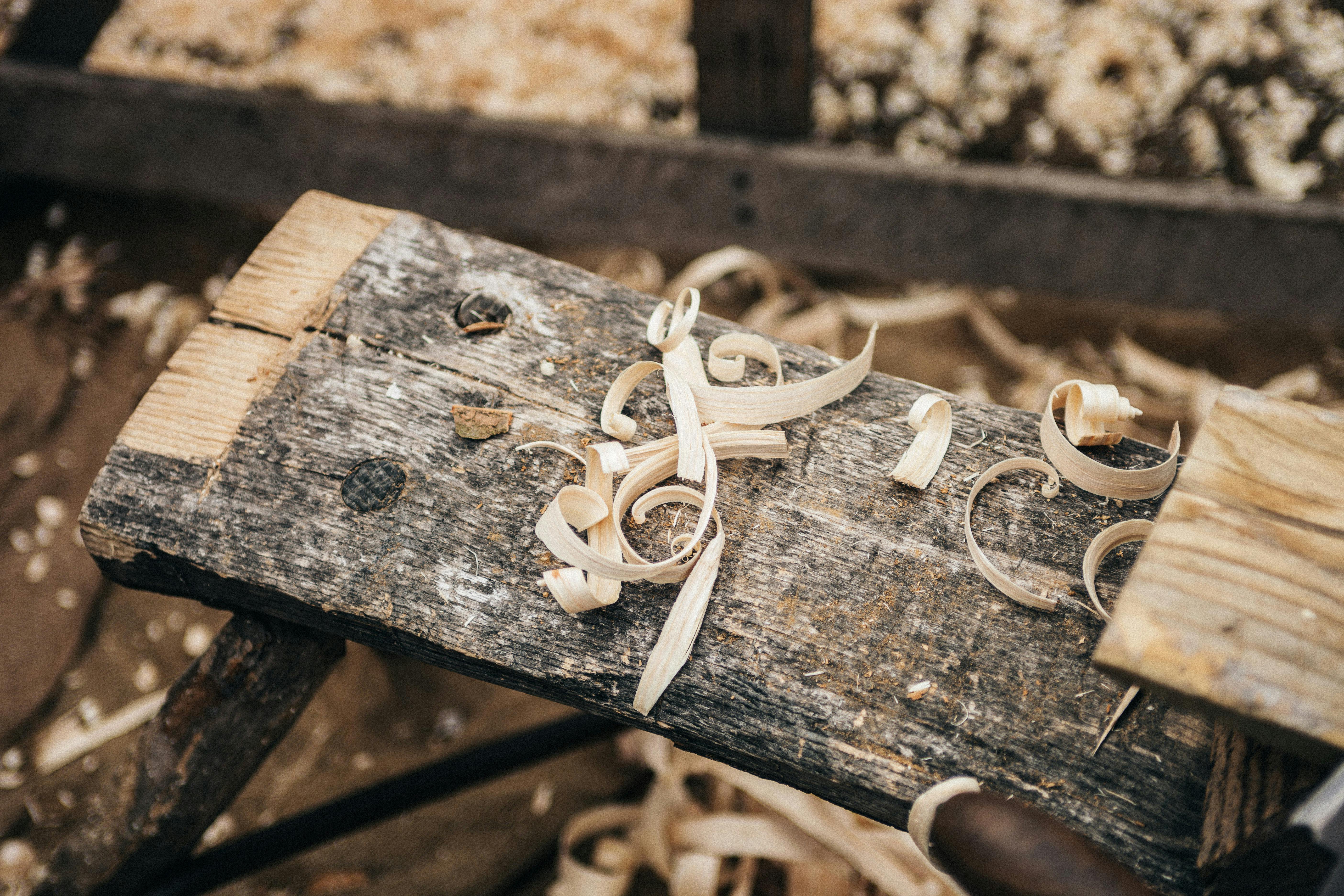 Ein mit Schnur zusammengebundenes Holzbrett liegt auf einer rustikalen Oberfläche, umgeben von verstreuten Holzspänen.