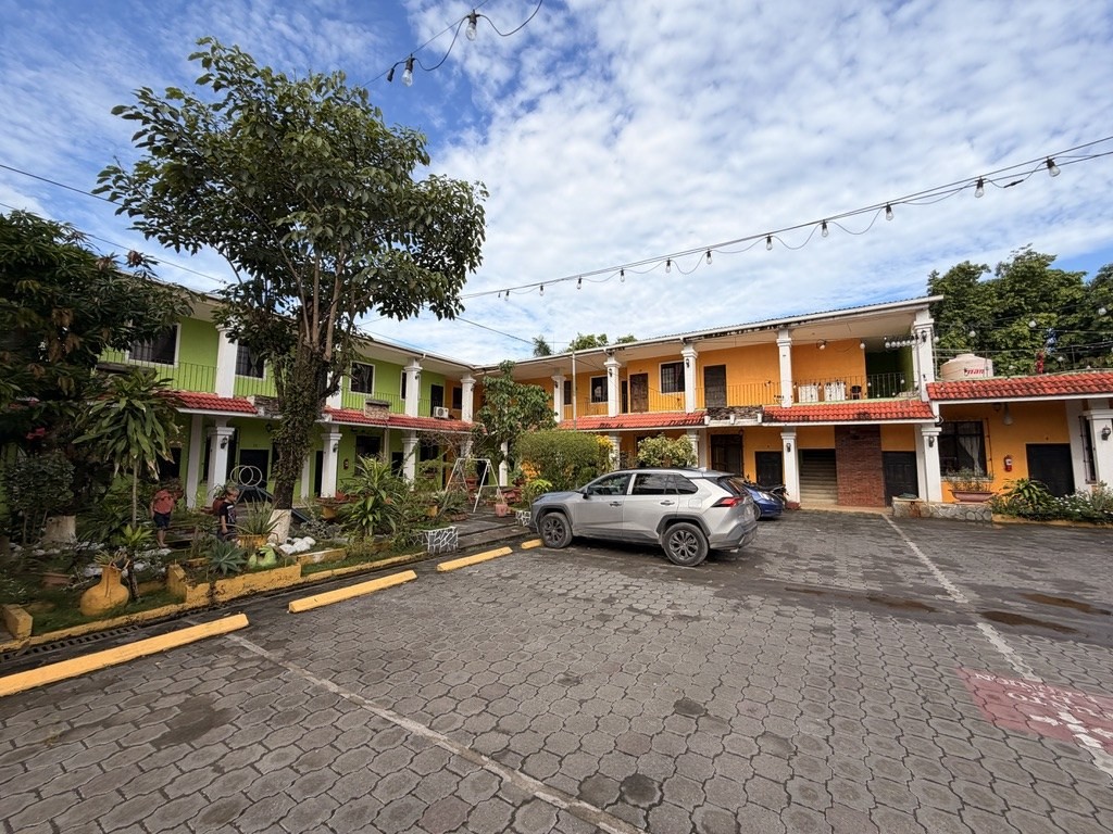 A small two-storey roadside hotel with the car parked in the courtyard.